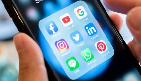 BANGKOK, THAILAND- 26 June 2019 : Hands of man use Iphone 7 plus with social media application of facebook, youtube, google search, instagram, twitter, linked in, line whatsapp, and pinterest on black background