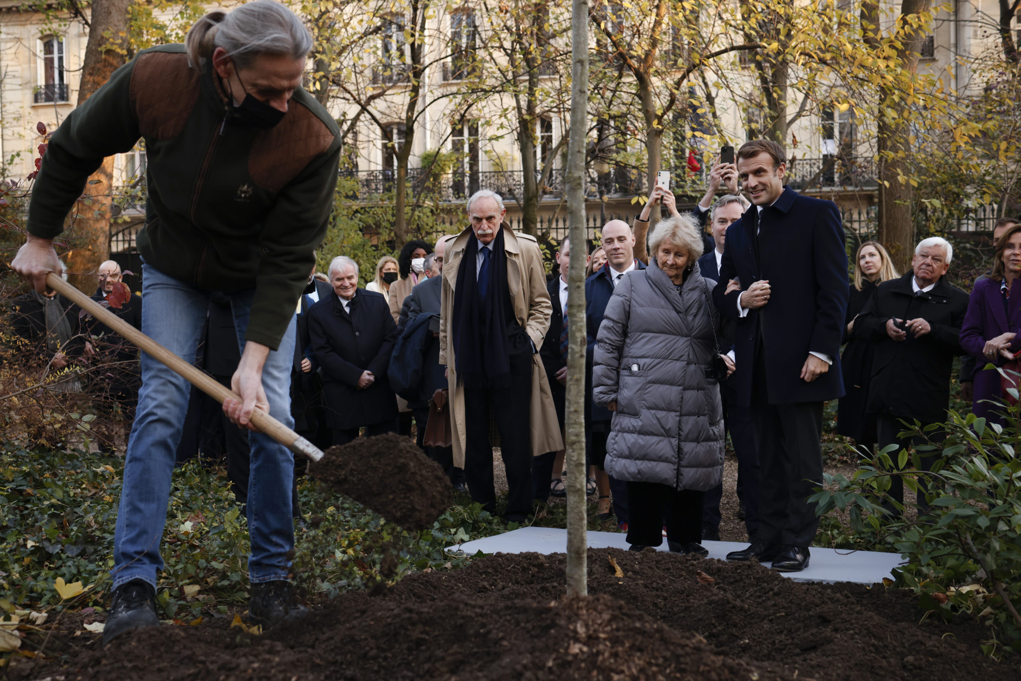 French President Emmanuel Macron and Canadian writer Antonine Maillet, watch a Gardner planting a tree in the garden of the Elysee Palace prior an awarding ceremony in Paris, Wednesday, Nov. 24 , 2021. Antonine Maillet was awarded with the Legion of Honor. (Yoan Valat/Pool Photo via AP)