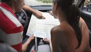 Rear view of a young couple with map sitting in the car